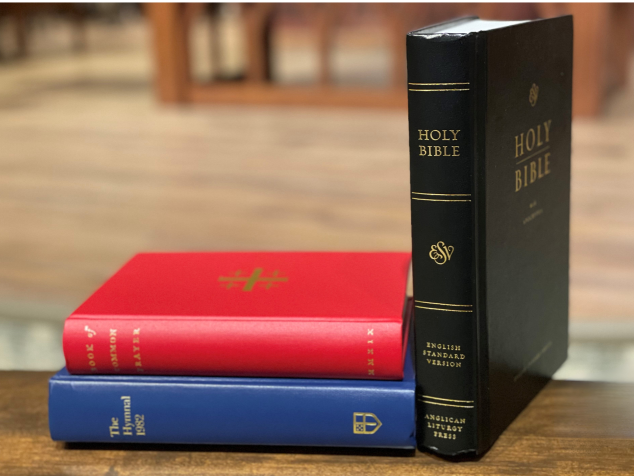 Three religious texts stacked on a wood table