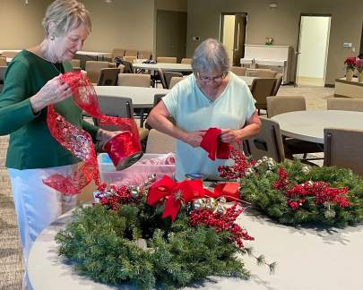 Two women decorating Christmas wreaths