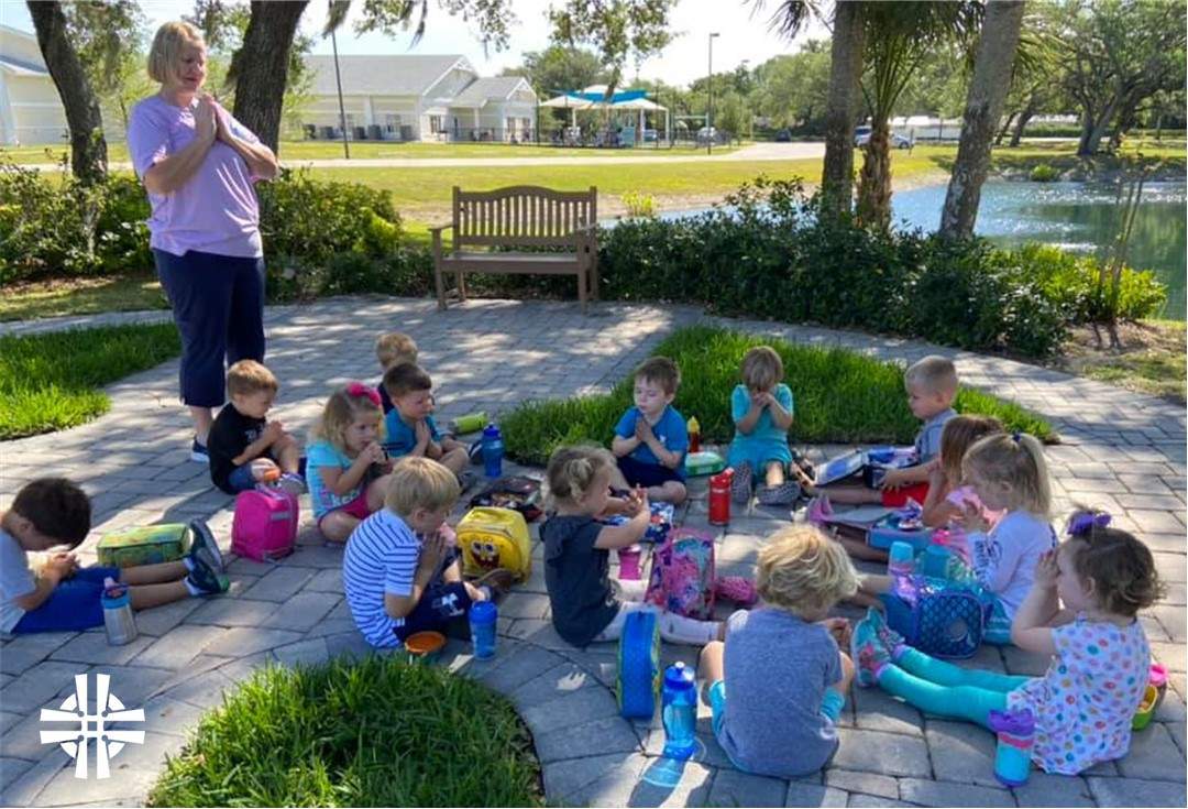 Pre-school children sitting on the ground saying prayers