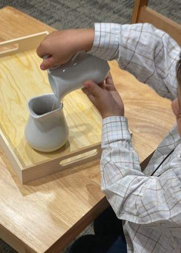 little boy pouring into ceramic cup